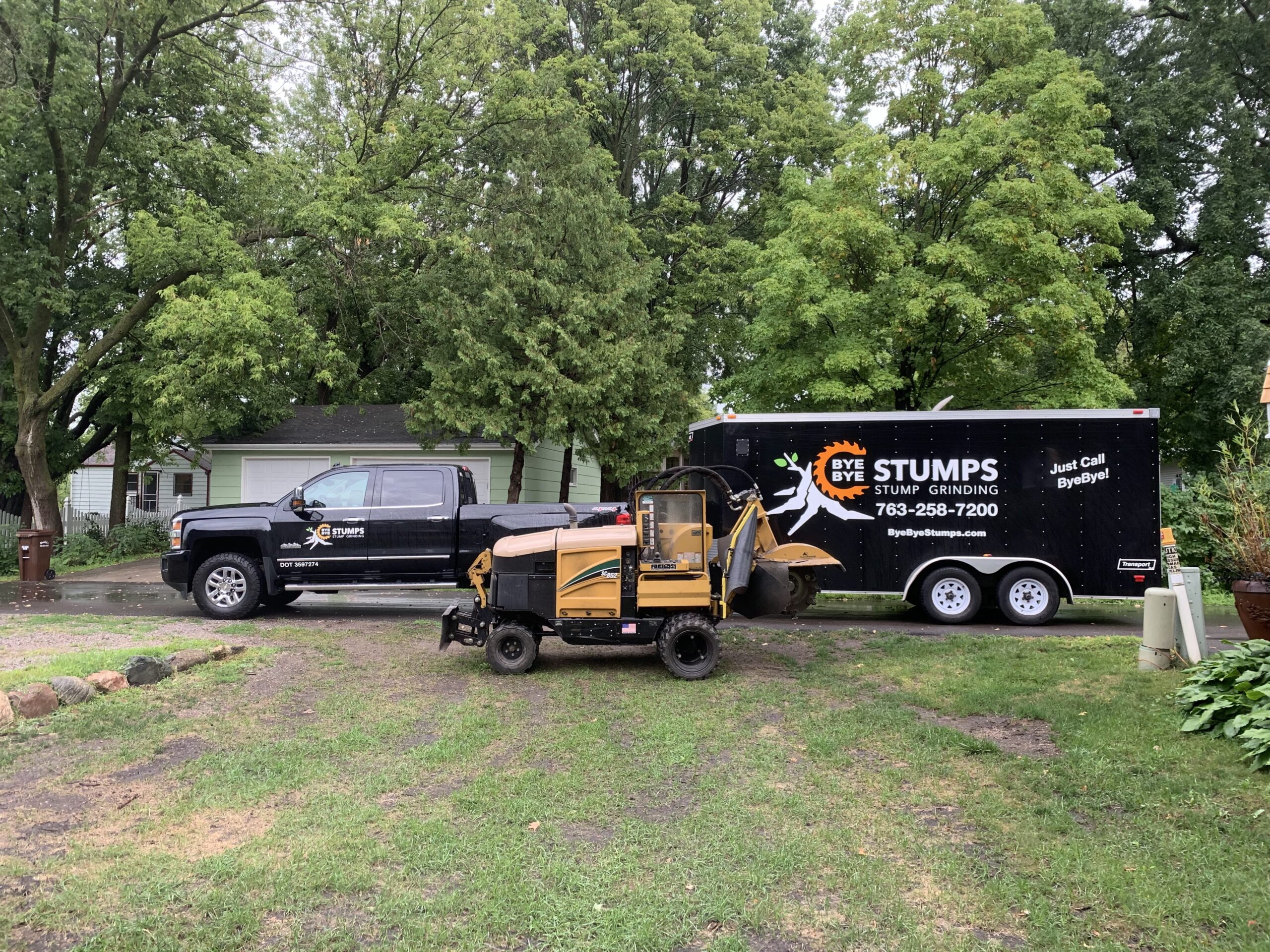 black pick up truck and trailer in yard next to grinding machine - tree stump grinding