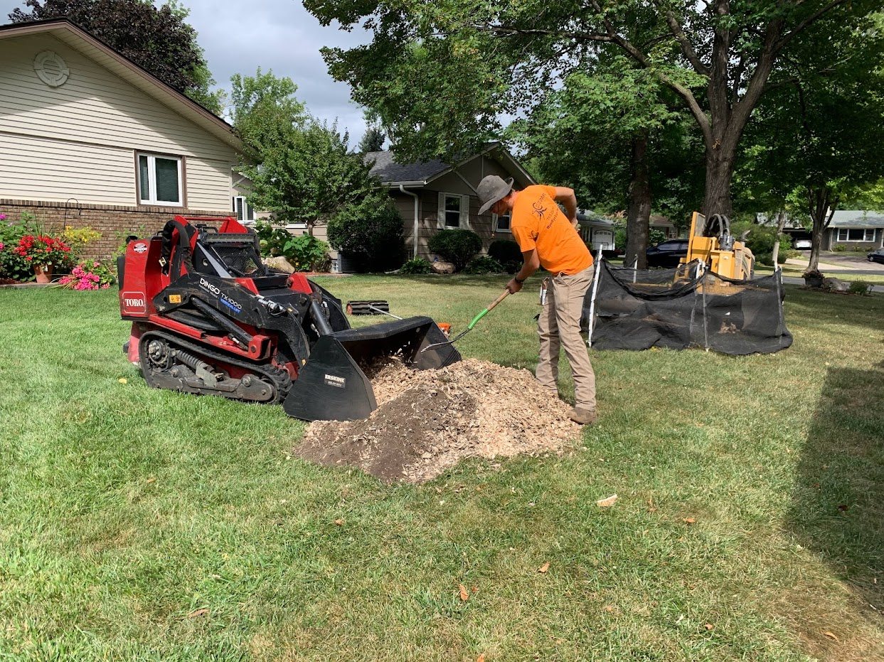 Man using pitchfork to shovel dirt - tree stump grinding